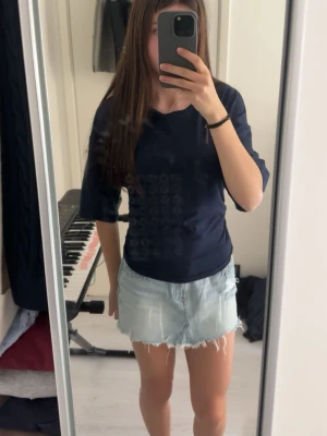 Mörkblå topp från Gina Tricot - Säljer en mörkblå topp med halvlånga ärmar och ”rynkade” sidor som ger en snygg passform. Toppen har en enkel, stilren design och är tillverkad i ett mjukt material som känns skönt mot huden.