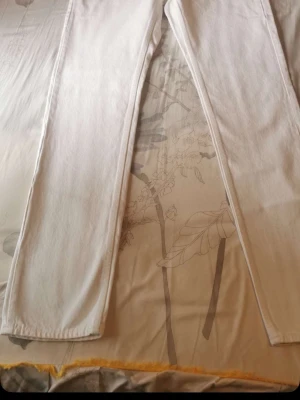 Vita raka jeans - Säljer ett par vita jeans med rak passform och klassisk femficksdesign. Jeansen har hög midja och är tillverkade i ett kraftigare denimtyg som ger en snygg siluett. Perfekta att styla med sneakers eller boots för en clean look.