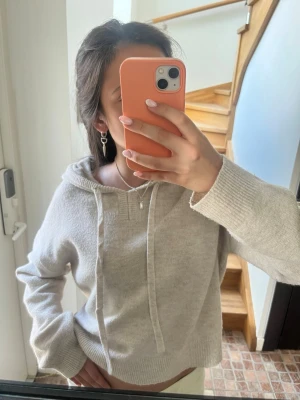 Beige stickad hoodie  - Mysig beige hoodie med huva och breda dragsnören. Tröjan har en avslappnad passform, ribbade muddar vid ärmslut och nederkant samt är tillverkad i ett mjukt stickat material. Perfekt för en chill och bekväm stil💗