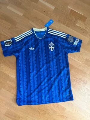 Sveriges VM tröja 2026 borta  - Säljer Sveriges VM borta tröja från Adidas 💙⚽️  Riktigt clean design med Sverige-märket på bröstet och Adidas-ränder på axlarna. Perfekt både till match eller vardag.  Storlek: XL2 OBS: Tröjan är liten i storleken, så du som brukar ha XL borde ta en eller till och med två storlekar större för bästa passform.  Helt ny med tags kvar 🔥 Passa på innan den försvinner