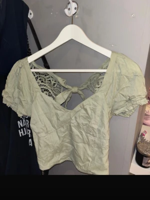 Ljusgrön croppad blus med spetsdetaljer - Söt ljusgrön topp. Den är croppad och med spets i ryggen. Aldrig använd och lapp sitter kvar. Från hollister. 