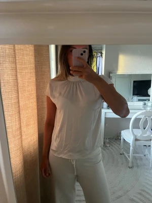 Krämvit blus med hög krage - Säljer en krämvit satin blus som jag endast använt en gång.