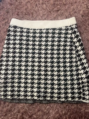 Svartvit elegant kjol~river Island - Trendig svartvit kortkjol med stort mönster och bred ribbad midja. Kjolen har en klassisk A-linjeform och är stickad i mjukt material som ger en skön känsla. Perfekt för dig som vill ha en statement piece i garderoben.