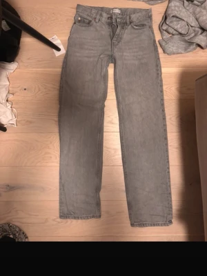 Grå raka jeans från Gina - Snygga grå jeans från Gina med rak passform och klassisk femficksdesign. Jeansen har bälteshällor, knappgylf och är tillverkade i ett mjukt denimtyg som passar perfekt till en avslappnad stil. Inga skador som jag vet om