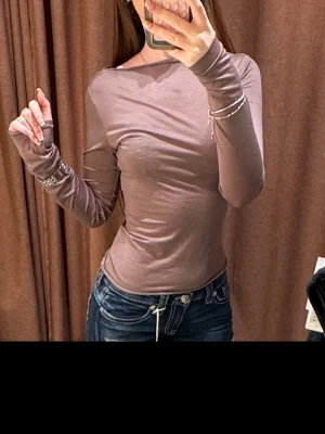 Ljusbrun långärmad topp - Säljer en ljusbrun långärmad topp med tight passform och rund hals. Toppen är enkel och stilren, perfekt att matcha med jeans eller kjol. Materialet känns mjukt och stretchigt, vilket gör den bekväm att bära hela dagen.