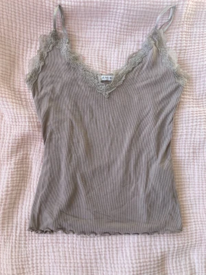 Ljuslila ribbad linnetopp med spets - Supersöt ljuslila ribbad linnetopp från AIM'N med tunna axelband och v-ringning. Toppen har fina spetsdetaljer längs urringningen och runt ärmhålen. Perfekt att styla med jeans eller kjol för en chill look.