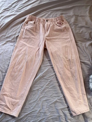 Ljusrosa manchesterbyxor H&M - Säljer ett par ljusrosa manchesterbyxor från H&M med avslappnad passform och resår i midjan. Byxorna har raka ben, knappgylf och klassiska fickor fram. Perfekta för en chill och trendig look.