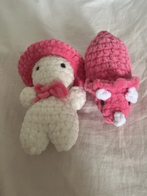 Virkade mjukisdjur i vitt och rosa - Två handgjorda virkade mjukisdjur, ett vitt med rosa hatt och rosett samt ett rosa djur med vita detaljer. Båda är gjorda i mjukt, fluffigt garn och har enkla broderade ansikten. Perfekta som dekoration eller present.( Har en liten fläck på benet.)
