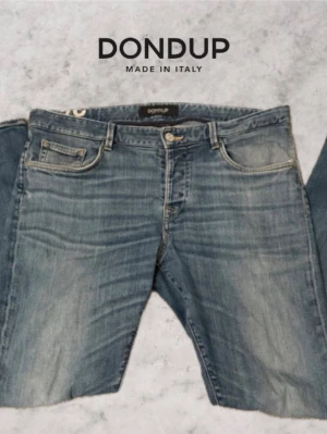 Blå jeans från Dondup - Snygga blå jeans från Dondup, tillverkade i Italien. Klassisk femficksmodell med raka ben och slitna detaljer för en avslappnad look. Jeansen har ljus tvätt och subtila kontrastsömmar. Perfekta för dig som gillar en casual och trendig stil.