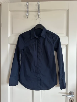 Mörkblå skjorta med långa ärmar - Mörkblå skjorta med krage och långa ärmar. Skjortan har knappar framtill och alla knappar sitter kvar. Köpt på sellpy. Står ingen storlek men passar xs/s. Märket är stile benetton💕