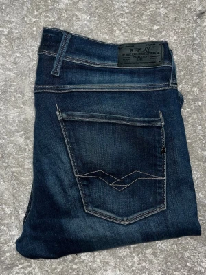 Replay Anbass jeans - Säljer ett par mörkblå jeans från Replay med snygga slitningar och kontrastsömmar. Klassisk femficksmodell med raka ben och läderpatch bak i midjan. Perfekta för dig som gillar en stilren men ändå avslappnad look. Midja 44cm. Se defekt på bakfickorna! JAG SKICKAR EJ FLER BILDER PÅ JEANSEN! för storleksguide hänvisar jag till måtten och för bättre inblick i passformen rekommenderar jag att googla på modellnamnet. :) 1,105