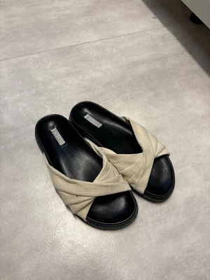 Beige slip-in sandaler från Nelly - Beiga slip-in sandaler från Nelly. Använda fåtal ggr, har dock lite fläckar, men det går nog att få bort.  Storlek 39.