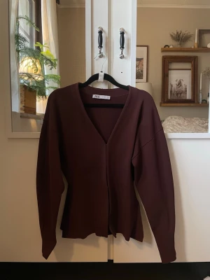 Brun kofta från Zara med v-ringning - Säljer en stilren vinröd tröja från Zara med djup v-ringning och långa ärmar. Tröjan har en enkel, rak passform och är tillverkad i ett stretchigt material som känns skönt mot huden. Storlek S, har knappt använt den. Pris kan diskuteras💕💕