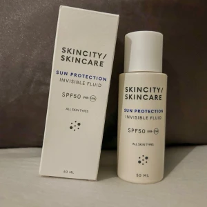 SKINCITY Sun Protection SPF50 - Solskyddsfluid från SKINCITY med SPF50 och UVA-skydd. Produkten är en lätt, osynlig vätska som passar alla hudtyper. Förpackningen är vit med svart och blå text och innehåller 50 ml. Perfekt för dig som vill ha ett effektivt solskydd i din hudvårdsrutin.