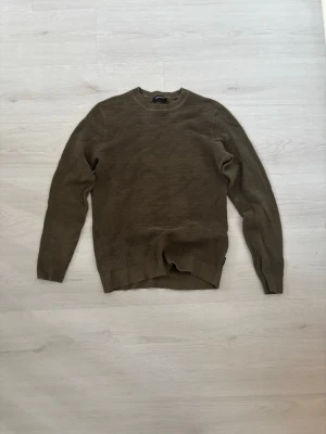 Olivgrön stickad tröja Jack & Jones - Säljer en olivgrön stickad tröja från Jack & Jones. Tröjan har rund halsringning, diskret ribbad struktur och långa ärmar. Perfekt för dig som gillar enkel och stilren design. Materialet känns mjukt och bekvämt.