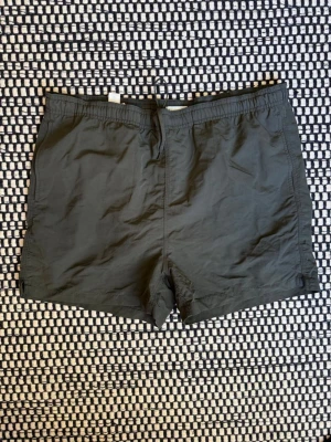 Mörkgröna badbyxor med ficka - Arket Badbyxor Strl: M/L. Stor i midjan: 88  Säljer många Herrkläder just nu. Kolla gärna mina andra annonser genom att klicka på min profil. Paketpris kan diskuteras.