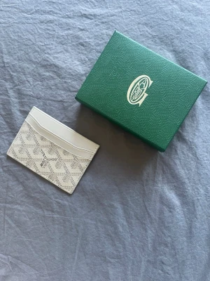 Vit korthållare - Säljer ett stilrent vitt kortfodral. Kortfodralet har flera fack för kort och är tillverkat i exklusivt läder. Perfekt för dig som vill ha något både snyggt och praktiskt.