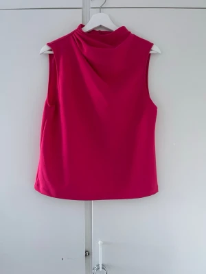 Rosa polotopp från Zara - Säljer en snygg rosa polotopp från Zara. Toppen är ärmlös och har en hög krage som ger en trendig look. Perfekt att matcha med jeans eller kjol för en cool outfit.