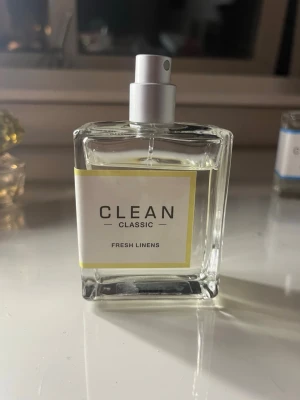 CLEAN Classic Fresh Linens parfym - Fräsch parfym från CLEAN i doften Fresh Linens. Flaskan är genomskinlig och fyrkantig med vit etikett och gul ram. Spraymunstycke i silverfärg. Perfekt för dig som gillar rena och lätta dofter. 80% kvar