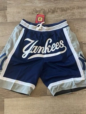 Blå Yankees shorts med snörning - Snygga blå shorts från Mitchell & Ness med Yankees-tryck framtill. Shortsen har vita och ljusgrå detaljer, bred resår i midjan och snörning. Perfekta för en sportig look och sköna att bära under varma dagar.