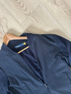 Mörkblå cardigan/overshirt Polo Ralph Lauren - Säljer nu denna feta overshirt/cardigan från märket Ralph Lauren! Svår att få tag på och den är dessutom i ett mycket bra skick, några små fläckar finns men den tvättas givetvis innan den skickas. Storlek S, vid frågor hör av er! 