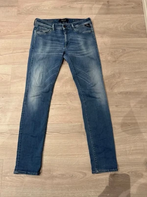 Jeans Replay - Säljer ett par Replay Hyperflex jeans i klassisk blå tvätt med snygga slitningar och broderade bakfickor. Modellen är slim och har normal midja. Jeansen är stretchiga och riktigt sköna, perfekta till vardagslooken. Materialet är en mjuk jeansblandning.