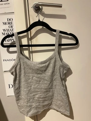 Grå ribbad linnetopp från H&M - Säljer en enkel och stilren grå ribbad linnetopp från H&M. Toppen har smala axelband och är tillverkad i mjuk bomull, perfekt för varma dagar eller som lager under en hoodie. Passar dig som gillar en avslappnad och trendig look. Skickar helst med PostNord😄