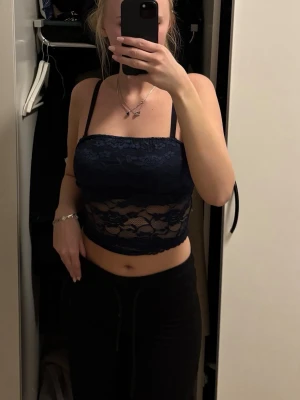 Mörkblå spetslinnetopp  - Snygg mörkblå linnetopp i spets croppad passform. Toppen har genomskinliga partier och en feminin look som passar perfekt till jeans eller kjol.