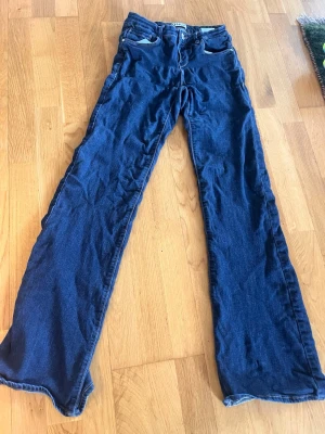 Mörkblå bootcut jeans - Snygga mörkblå bootcut jeans med klassisk femficksdesign och låg midja. Jeansen har vida ben och är tillverkade i denim, perfekt för en avslappnad och trendig look.