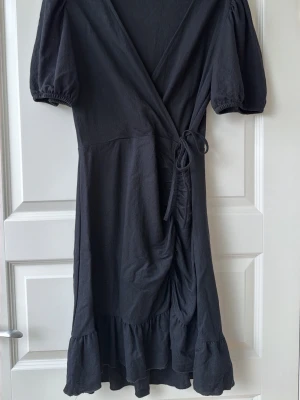 Svart klänning från Gina Tricot  - Svart omlottklänning från Gina Tricot i strl L!