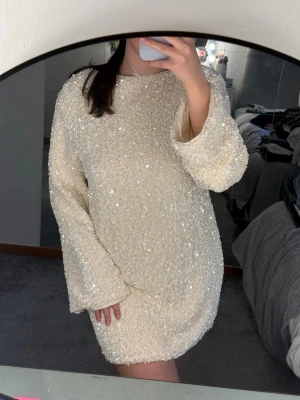 Glittrig kort klänning med rosett - Superfin glittrig kort klänning i ljus färg med öppen rygg och stor svart rosett. Klänningen säljs inte mer på hm🤍 Klänningen har aldrig använts 