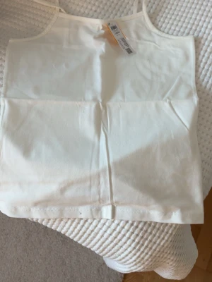 Vit ärmlös linnetopp i bomull - Säljer ett enkelt och stilrent vit linne från Lindex. Aldrig använt. Tveka inte av att höra av er om ni har fler frågor om linnet!