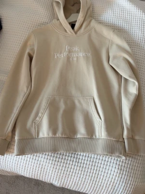 Beige hoodie från Peak Performance - Snygg beige hoodie från Peak Performance med broderad logga på bröstet. Använd 4 gånger inga synliga defekter på hoddien.