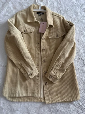 Beige manchester overshirt Missguided - Overshirt i beige manchester från Missguided. Klassisk skjortkrage, två bröstfickor med knappar och långa ärmar. Stängs med knappar framtill. Aldrig använd💕skriv om du vill ha fri frakt 🚚 Oversize modell 