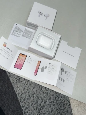 Apple AirPods Pro med laddningsetui - Säljer ett par vita Apple AirPods Pro med trådlöst laddningsetui. Hörlurarna har en stilren och kompakt design i blank plast och levereras med originalförpackning, laddningskabel och instruktioner. Perfekta för dig som vill ha brusreducering och smidig anslutning till iPhone.