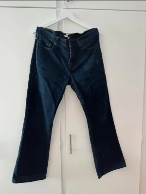 Levi's 515 Bootcut Jeans mörkblå - Snygga mörkblå Levi's 515 bootcut jeans med klassisk femficksmodell och läderpatch bak i midjan. Jeansen har en något utsvängd passform nedtill och är tillverkade i slitstark denim. Perfekta för dig som gillar en retro och avslappnad stil.