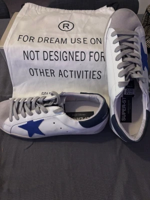 Golden Goose Superstar sneakers blå stjärna - Golden Goose sneakers i vitt läder med blå mockastjärna på sidan. Kommer med orginal skolåda och dustbag! Pris kan diskuteras🤝Hör av dig vid frågor!