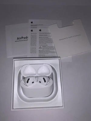 Apple AirPods 4 - Säljer ett par vita Apple AirPods Pro med aktiv brusreducering och trådlöst laddningsetui. Snygg och kompakt design i blank plast, perfekt för dig som vill ha grymt ljud och smidig anslutning till din iPhone eller andra Apple-enheter.