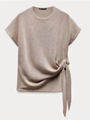 Beige topp med knyt från Zara - Säljer denna stilrena och trendiga beigea toppen från Zara med korta ärmar💕.  Toppen har en snygg knytdetalj i sidan som ger en cool twist. Perfekt att matcha med jeans eller kjol för en trendig look.