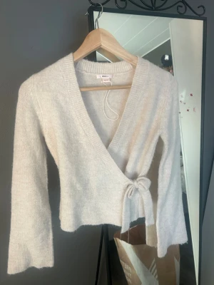 Beige omlottkofta från Gina Tricot - Mysig beige stickad omlottkofta från Gina Tricot med knytband i sidan. Aldrig använd 