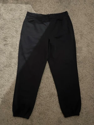 Mörkblåa mjukisbyxor från lager 157 - Säljer ett par mörkblåa mjukisbyxor med resår i midjan och vid bensluten. Byxorna har en enkel design och en bakficka. Perfekta för chill dagar eller när du vill vara bekväm. Materialet känns mjukt och stretchigt.