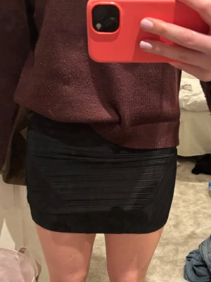 Svart tight kortkjol i stretch - Snygg svart kortkjol med tight passform och diskreta horisontella sömdetaljer. Kjolen är enkel och stilren, perfekt att matcha med olika toppar. Materialet känns stretchigt och följsamt.