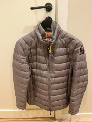 Grå Parajumper jacka - Säljer en grå pufferjacka från Parajumpers som är i toppskick! Perfekt nu för våren. Jackan har ett litet ihopsytt hål på ryggen som man inte kan se. Ny pris 3699. Jackan är i XS men passar definitivt S (är 184 och den passar mig). Lapp och extra knappar för loggan följer med! Priset är ej hugget i sten. Tveka inte på att höra av dig!!