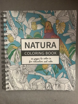NATURA målarbok spiralbunden - Säljer en spiralbunden målarbok med titeln NATURA. Boken har 64 sidor med naturmotiv som blommor och papegojor att färglägga. Omslaget är färgglatt med blå bakgrund och detaljer i vitt, gult och grönt. Perfekt för dig som gillar att slappna av med kreativitet.