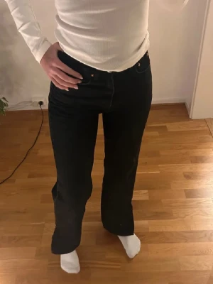 Svarta raka jeans från Gina tricot  - Säljer ett par svarta jeans med rak passform och hög midja. Klassisk femficksmodell med knapp och dragkedja framtill. Jeansen har en stilren look och passar perfekt till en avslappnad vardagsstil.