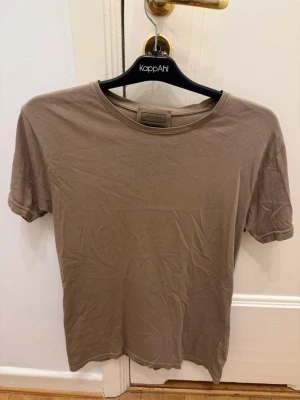 Brun kortärmad t-shirt antagon - En basic brun t-shirt från antagon med rund halsringning och korta ärmar. Tillverkad i mjuk bomull som är väldigt skön. Perfekt att matcha med jeans eller shorts för en enkel och clean look.