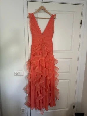 Volangklänning i korall med v-ringning - Asos luxe maxi-klänning. Helt ny med prislapp. Slutsåld på hemsidan. Säljs för ordinarie pris