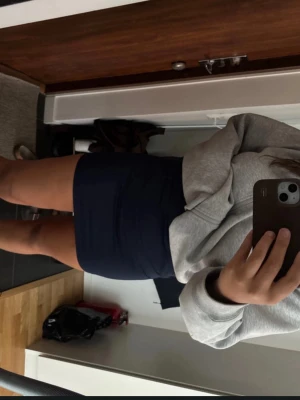 Mörkblå kortkjol i bomull - Enkel och stilren mörkblå kortkjol i bomull. Kjolen har en tight passform och är perfekt att matcha med en hoodie eller t-shirt. Klassisk design utan mönster eller detaljer, vilket gör den lätt att styla.