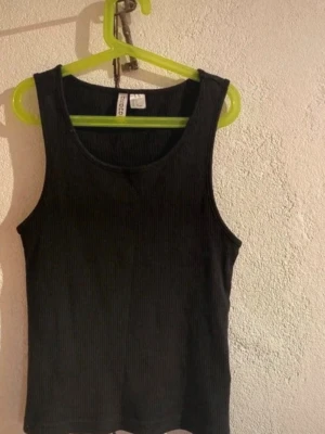 Svart ribbad linnetopp från H&M - Säljer en svart ribbad linnetopp från H&M Divided. Toppen är ärmlös med rund halsringning och har en tight passform. Perfekt att styla med jeans eller kjol för en enkel och snygg look💗