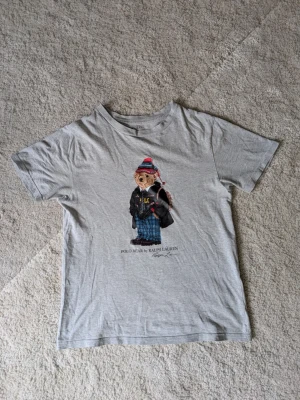 Ralph Lauren t-shirt - Tjosann! Säljer denna sjukt feta tröjan då den inte riktigt passar längre, sjukt snygg och trendig, unik och skön på sommaren 🌅. Normal - slim passform vilket är riktigt snyggt på t-shirts 🌌. Storlek: ~ 165cm ✅. Självklart äkta 💐. |Nypris = 999-1500kr ❌ | vårt pris = 239kr ✅. Inget og följer med samt en liten fläck över björnens huvud ( knappt synligt ) därför ett rimligt pris. Frågor? Hör av dig! 💬